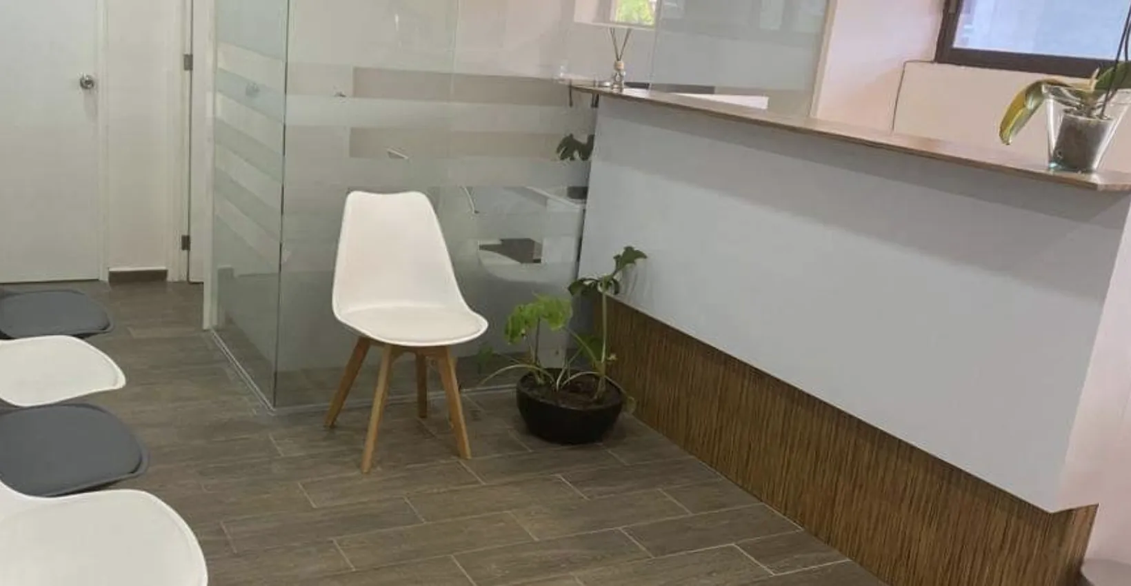 Sala de espera de Chalet Dental con sillas blancas y mostrador de atención